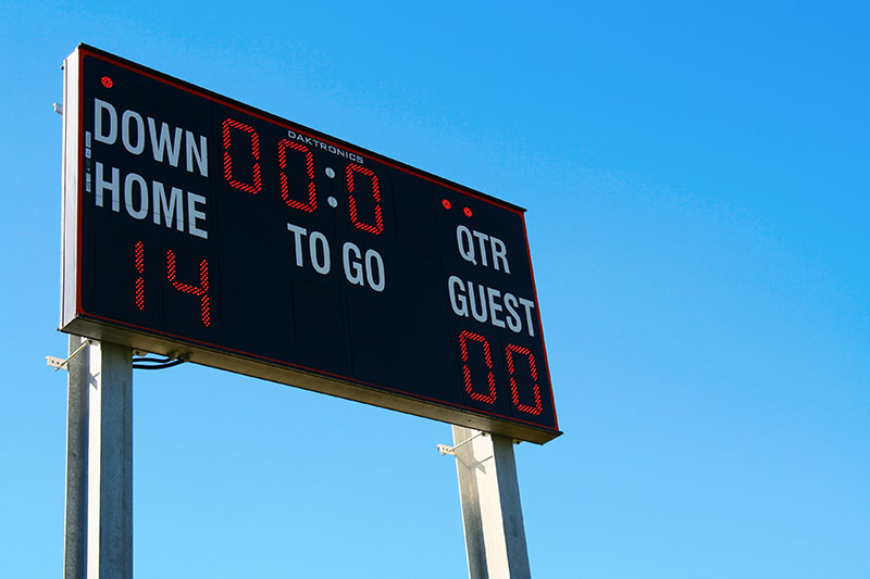 Home 234 A football scoreboard displays Home: 14, Guest: 0 with 0:00 time remaining, under a clear blue sky.