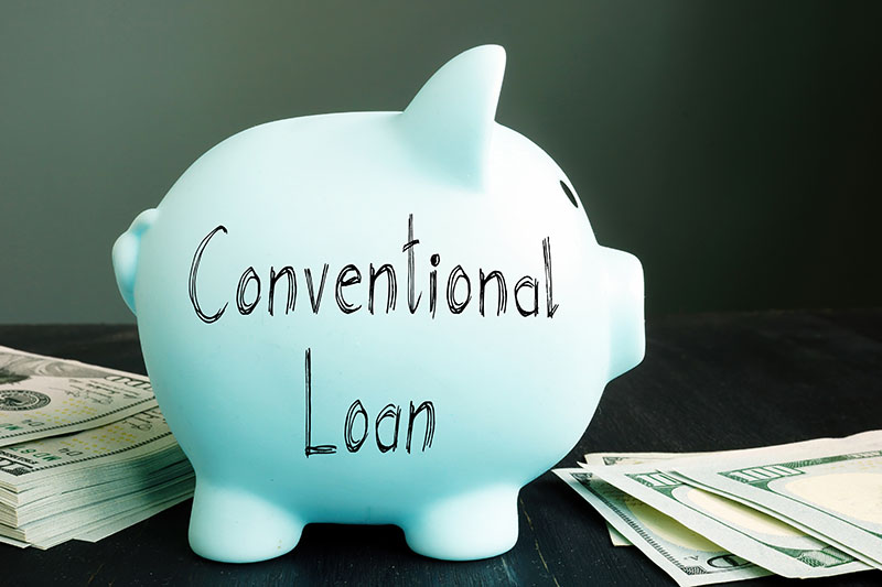 Home 226 A light blue piggy bank labeled Conventional Loan sits on a table next to stacks of U.S. dollar bills, against a dark background.