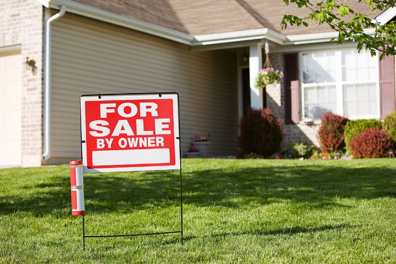 Home 189 A For Sale by Owner sign is displayed on the front lawn of a suburban house with beige siding, white trim, and maroon shutters on a sunny day.