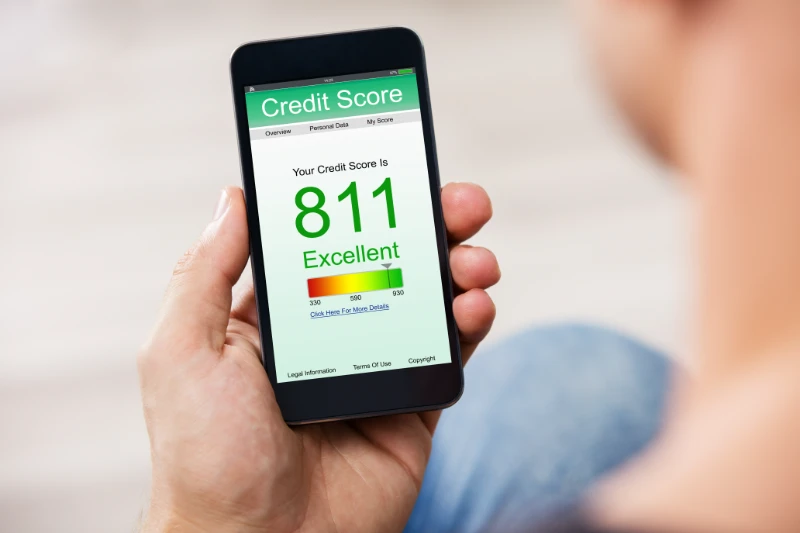 Home 37 A person holds a smartphone displaying a credit score of 811, labeled as Excellent, on a green-themed screen with a score range and navigation tabs visible at the top.