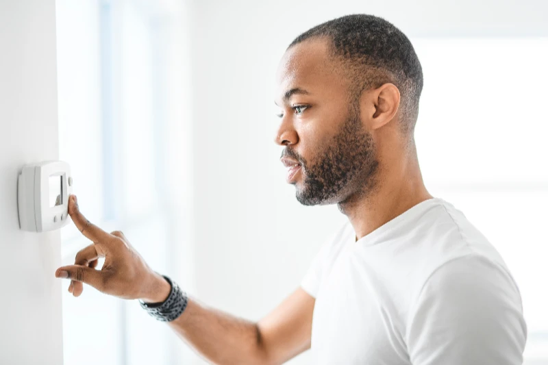 Home 26 A man choosing temperature on thermostat