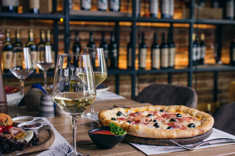 Home 21 Pizza with prosciutto and olives with wine in restaurant