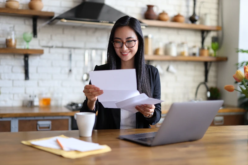 Home 14 Businesswoman happily reads financial letter at a desk with laptop