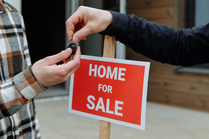 Home 8 Closeup of a home sale sign with people exchanging keys