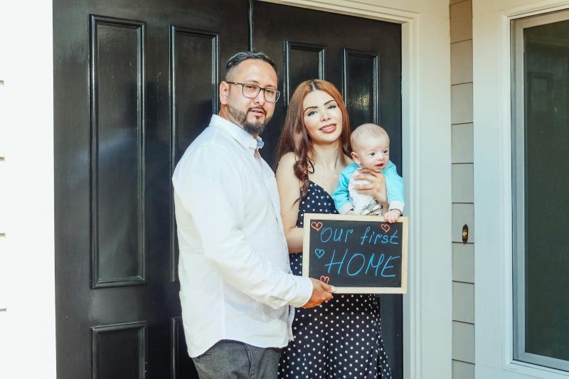 Home 6 Young family with baby golding sign Our First Home