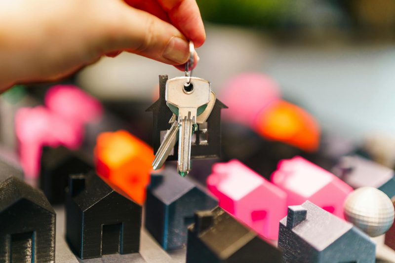 Home 3 Colorful miniature houses and a hand holding keys