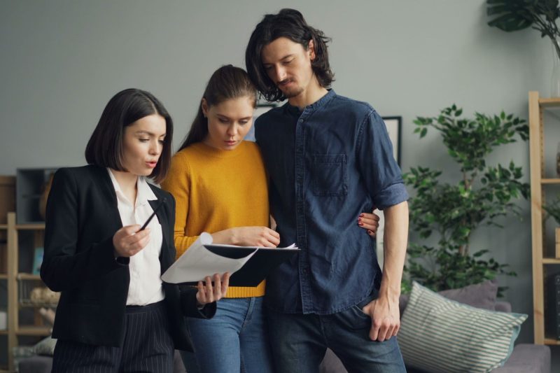 Home 12 A couple reviewing documents with a real estate agent indoor 1781629493