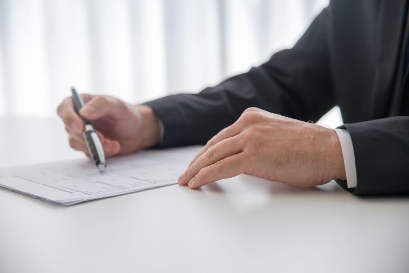 Home 12 Businessman signing important documents at office desk 1785258602